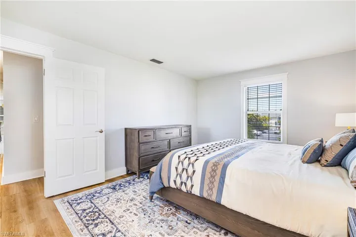 Bedroom featuring light-toned walls, wood-finish flooring, and white trim