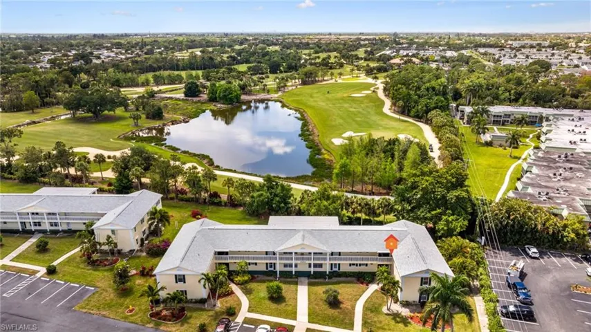 Aerial perspective showcasing residential buildings alongside a golf course and a prominent water feature