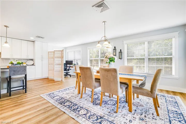Open-concept living area featuring wood-finish flooring, white cabinetry, and abundant natural light from multiple windows