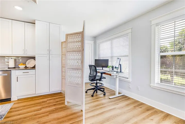 Bright interior space featuring light wood-finish flooring, white cabinetry, and a light gray backsplash