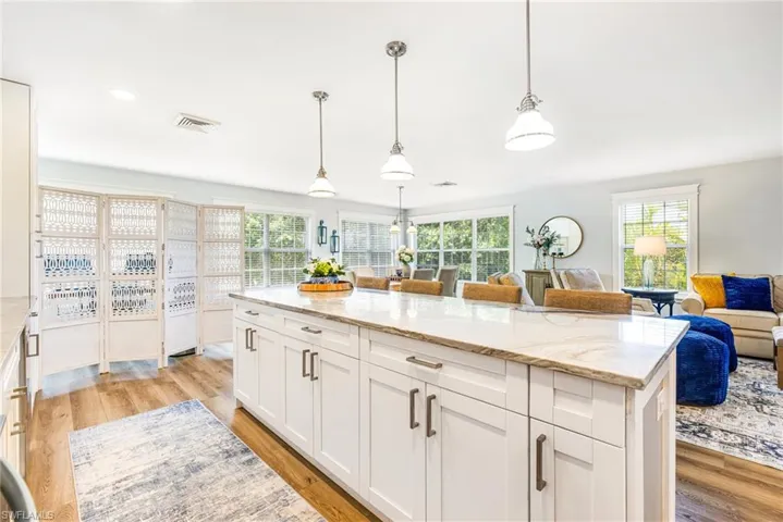 Kitchen island featuring a light-toned countertop, white cabinetry, and brushed nickel hardware