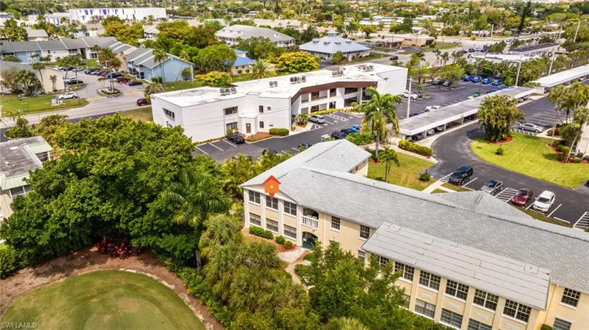 Aerial perspective showcasing a multi-story residential building with a light-colored exterior and a gray shingle roof