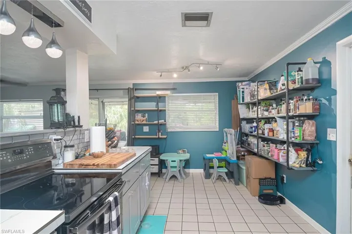 Kitchen featuring black electric range, ornamental molding, light tile patterned flooring, and plenty of natural light