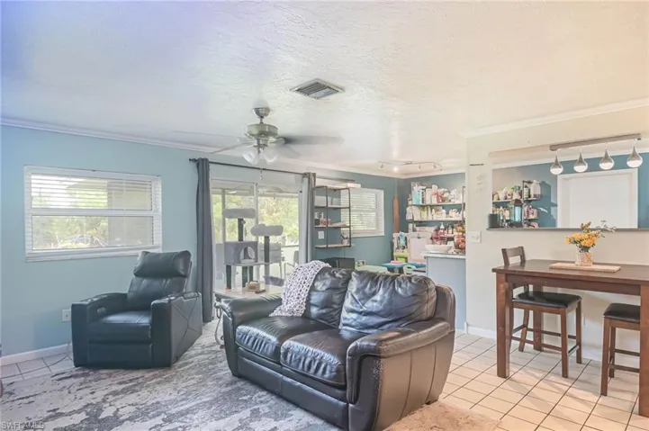 Living room with crown molding, plenty of natural light, and ceiling fan