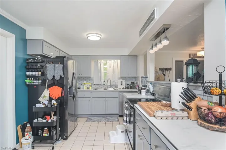 Kitchen with light tile patterned floors, decorative backsplash, ornamental molding, and stainless steel electric range oven