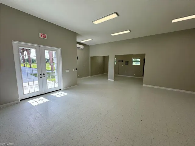 Tiled spare room with an AC wall unit and french doors