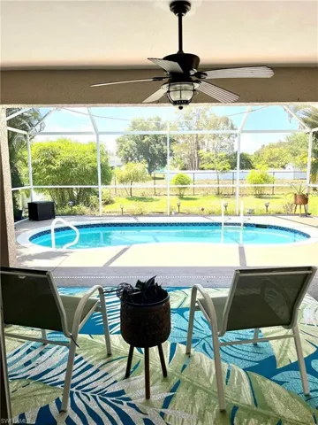 View of swimming pool with ceiling fan and a lanai