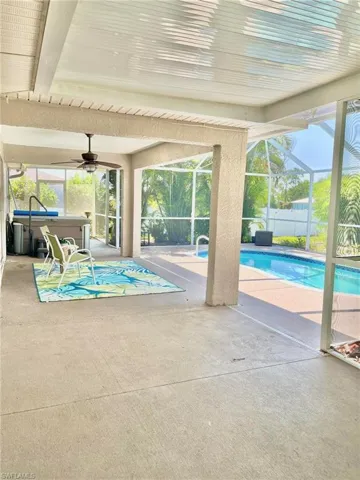 View of pool with an extended patio area, glass enclosure, and ceiling fan