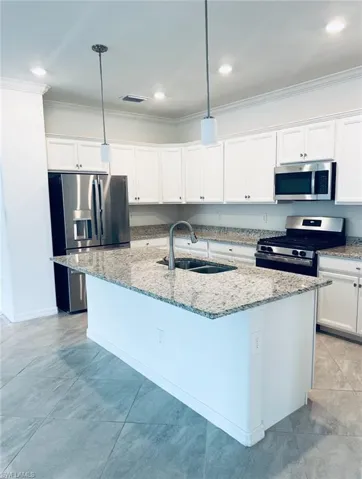 Kitchen featuring crown molding, a sink, granite counters, white cabinets, and stainless steel appliances.