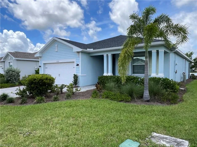 Ranch-style home with stucco siding, an attached garage, roof with shingles, and a front yard