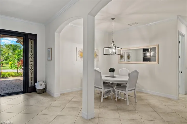 Tiled dining room with ornamental molding and a chandelier