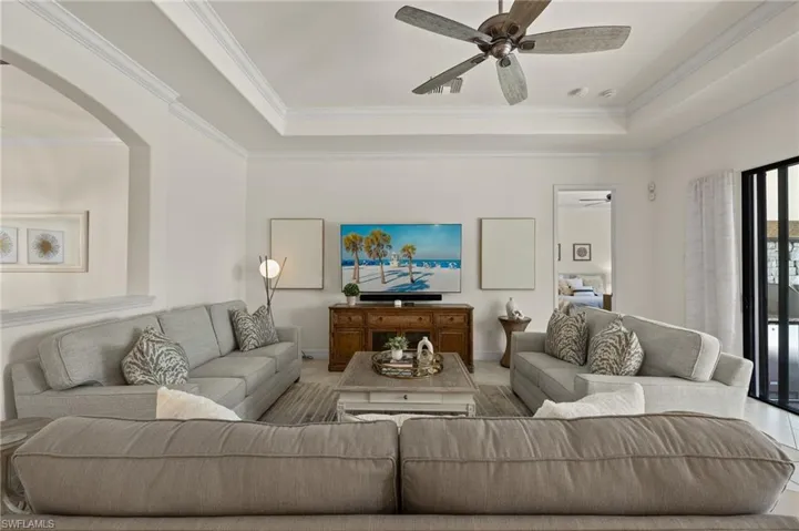 Living room featuring crown molding, a tray ceiling, and ceiling fan