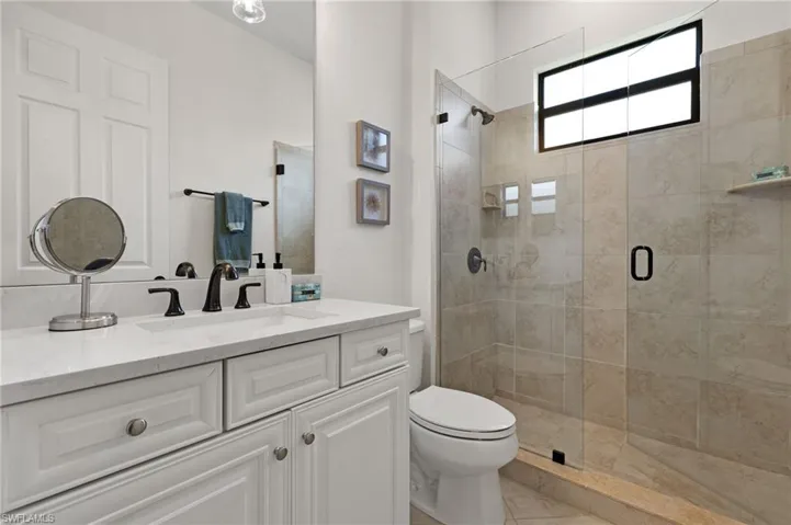 Bathroom featuring vanity, tile patterned flooring, toilet, and an enclosed shower