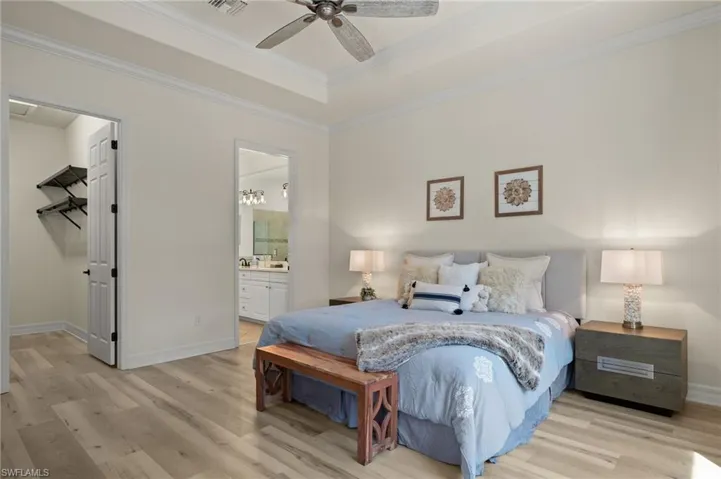 Bedroom featuring ceiling fan, ornamental molding, ensuite bath, and light hardwood / wood-style floors