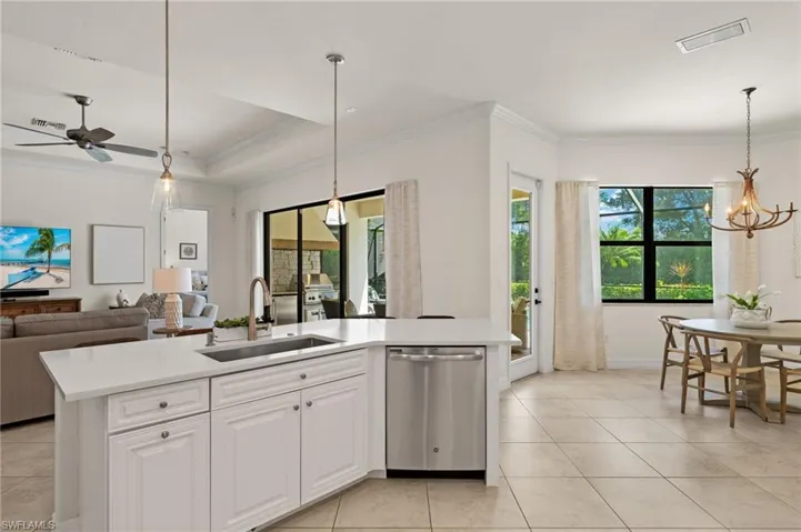Kitchen featuring ceiling fan with notable chandelier, a kitchen island with sink, dishwasher, and sink