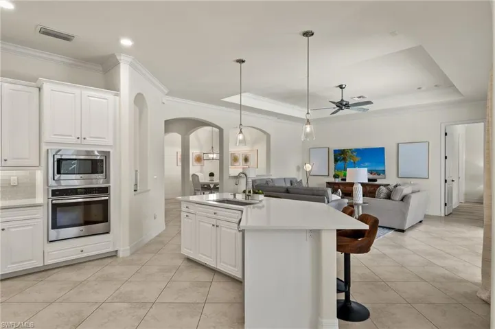 Kitchen featuring appliances with stainless steel finishes, an island with sink, white cabinets, ceiling fan, and sink