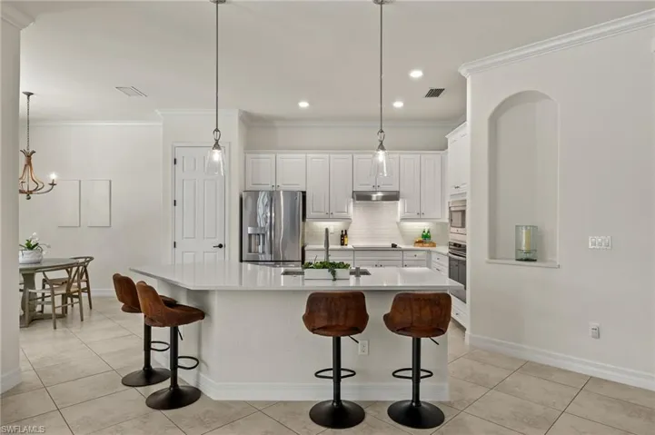 Kitchen with a kitchen island with sink, white cabinetry, and stainless steel appliances