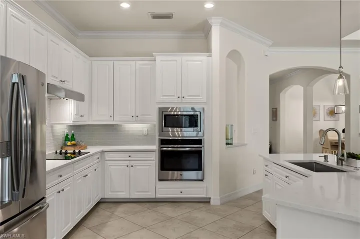 Kitchen with white cabinetry, sink, pendant lighting, and stainless steel appliances
