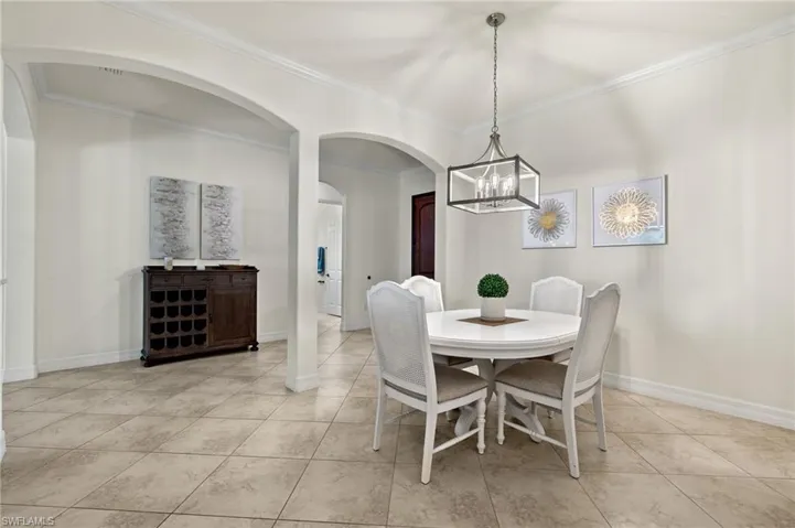 Tiled dining area featuring a chandelier and crown molding