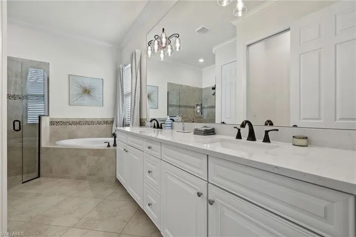 Bathroom with tile patterned floors, independent shower and bath, vanity, and crown molding