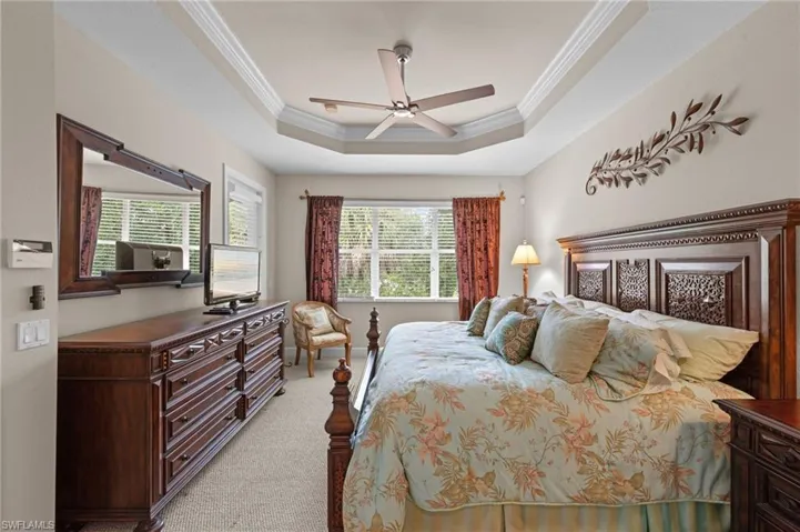 Bedroom featuring crown molding, light carpet, a ceiling fan, and a tray ceiling