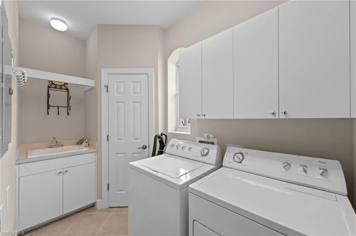 Washroom featuring cabinet space, light tile patterned floors, and washer and dryer