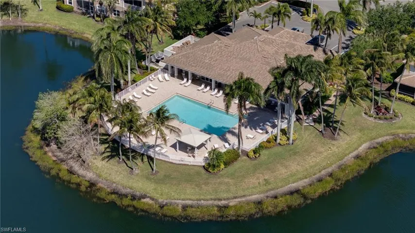 Waterfront clubhouse featuring a swimming pool, covered pavilion, hardscaped deck, and mature palm trees