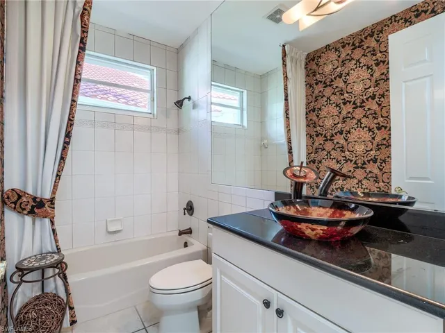 Full bathroom featuring shower / tub combo with curtain, vanity, toilet, and tile patterned floors