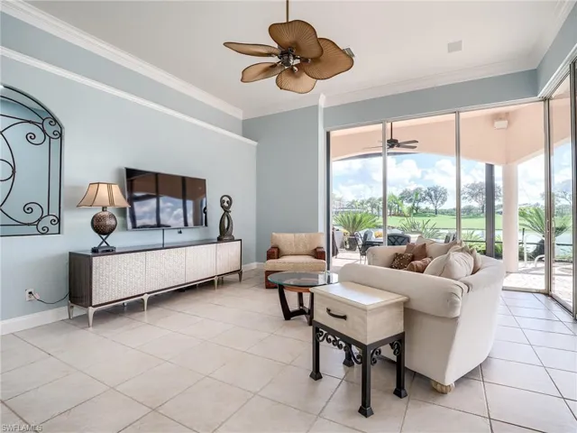 Tiled living room featuring ceiling fan and ornamental molding