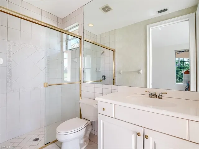 Bathroom with walk in shower, vanity, tile patterned flooring, and toilet
