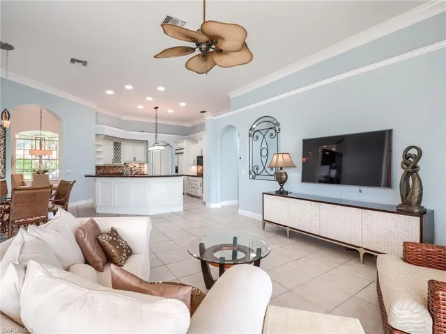 Living room featuring ornamental molding, ceiling fan, and light tile patterned floors