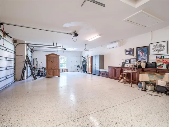 Garage featuring ceiling fan, a garage door opener, and a wall mounted air conditioner