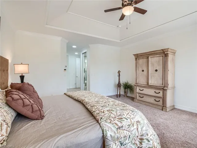 Bedroom featuring ceiling fan, light carpet, and ornamental molding