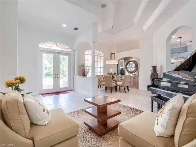 Living room with french doors, crown molding, and light tile patterned floors