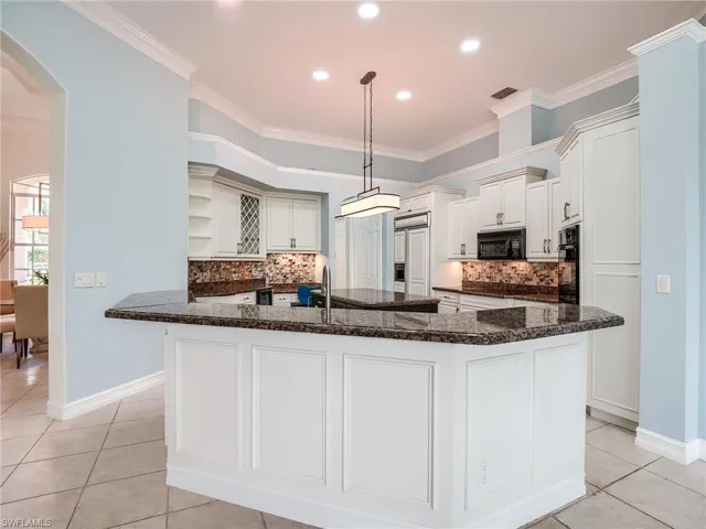 Kitchen featuring an island with sink, ornamental molding, and black appliances