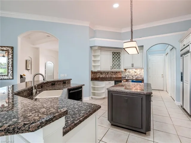 Kitchen featuring black dishwasher, a kitchen island with sink, sink, hanging light fixtures, and ornamental molding