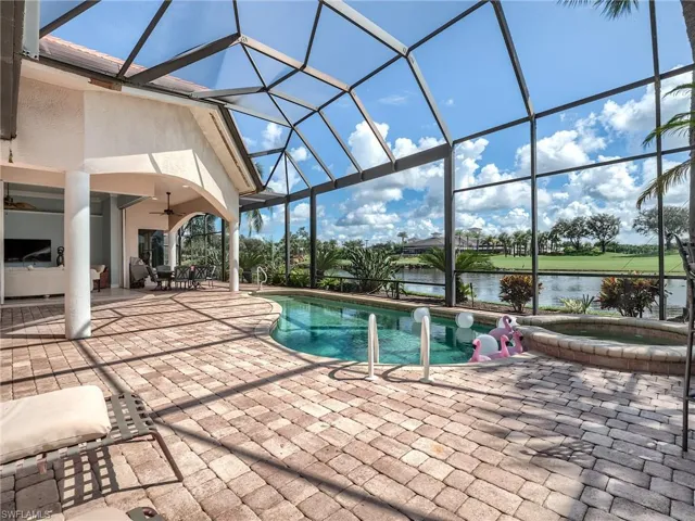 View of swimming pool featuring ceiling fan, an in ground hot tub, a patio area, screened enclosure, and a water view