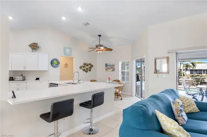 Kitchen featuring light tile patterned floors, visible vents, a breakfast bar, white cabinetry, and a sink