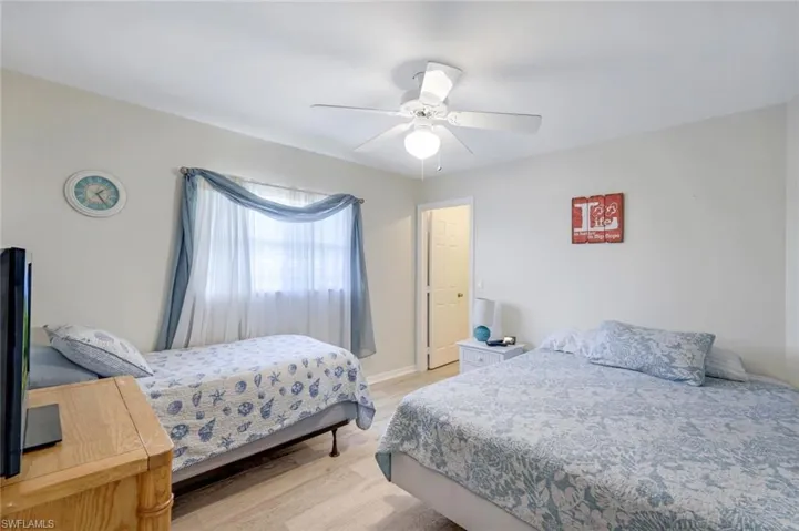 Bedroom with a ceiling fan, light wood-style flooring, and baseboards