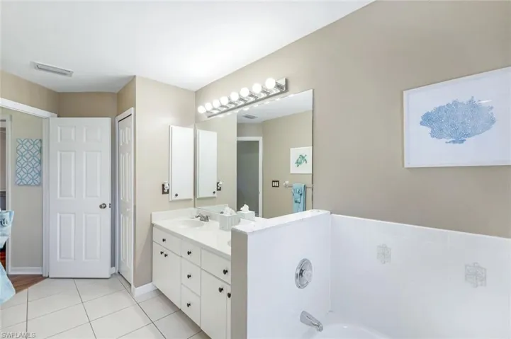 Full bathroom with visible vents, baseboards, a tub, tile patterned flooring, and vanity