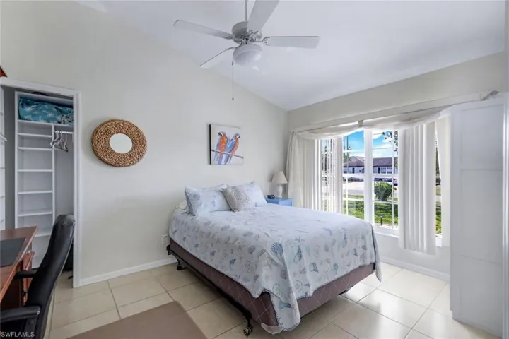 Bedroom featuring light tile patterned floors, baseboards, a walk in closet, vaulted ceiling, and a closet