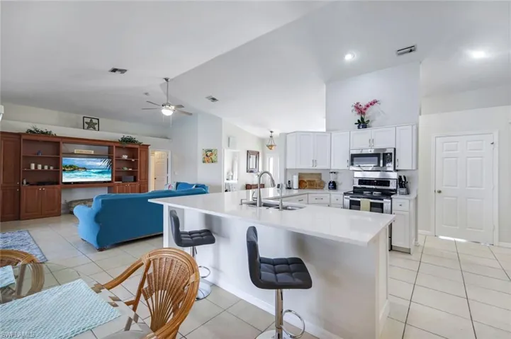 Kitchen featuring visible vents, appliances with stainless steel finishes, vaulted ceiling, light countertops, and a sink