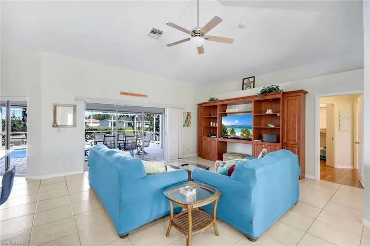 Living room with visible vents, baseboards, lofted ceiling, ceiling fan, and light tile patterned flooring