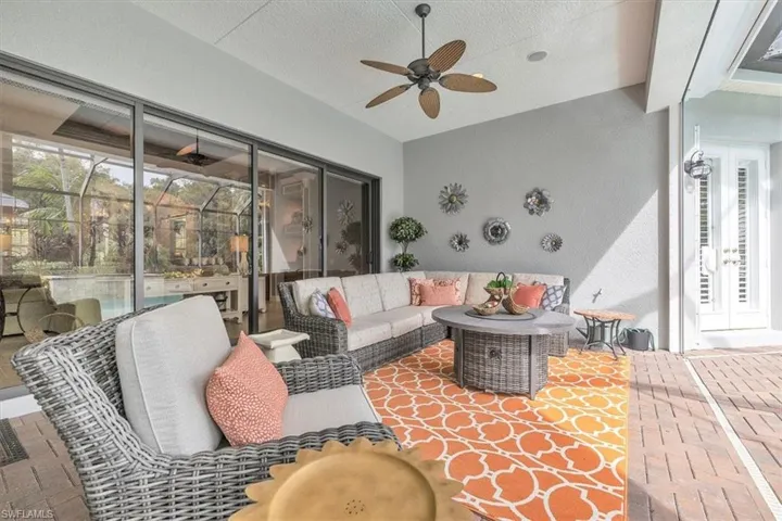 Covered outdoor patio featuring brick paver flooring, multi-panel sliding glass doors, a ceiling-mounted fan, and recessed lighting