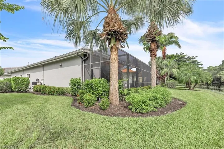 Screened-in patio enclosure, manicured lawn, mature palm trees, and professional landscaping