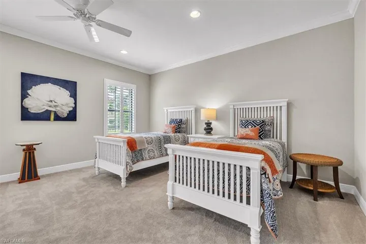 Spacious room featuring neutral carpeting, crown molding, plantation shutters, recessed lighting, and a white ceiling fan
