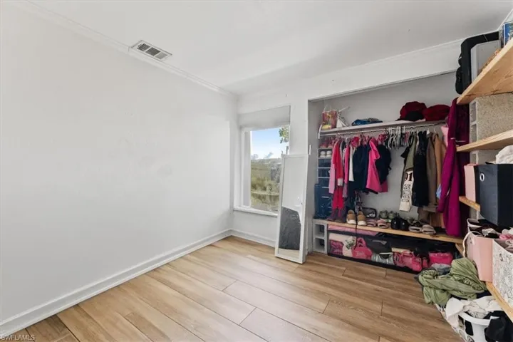 Bedroom featuring wood finished floors, a closet, and crown molding