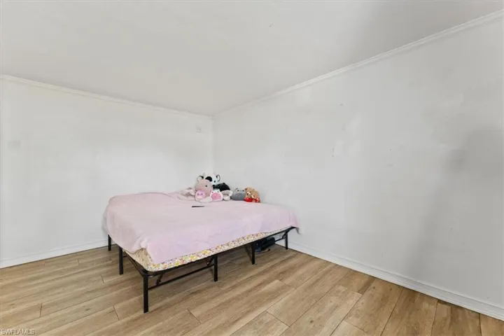 Bedroom with light wood-style flooring and crown molding