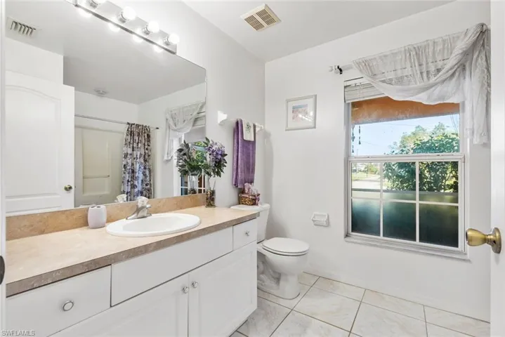 Bathroom featuring vanity, curtained shower, toilet, and tile patterned flooring
