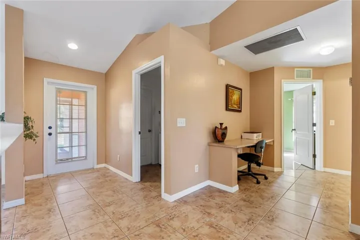 Office area featuring light tile patterned floors and vaulted ceiling